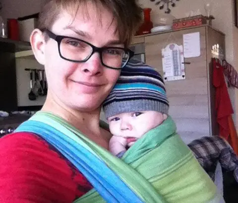 2015, ik verloor mezelf in het moederschap. Een foto van mij en mijn zoon in een draagdoek, waarbij je de vermoeidheid op mijn gezicht ziet.